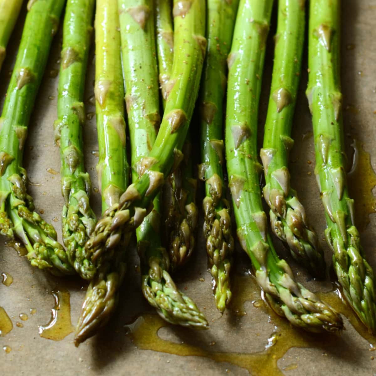 Trimmed asparagus drizzled with oil on a baking sheet.
