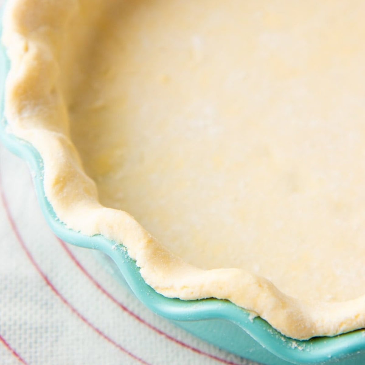 Unbaked gluten-free pie crust in a teal pie pan.