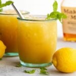 Glass of whiskey punch with crushed ice and a mint sprig.