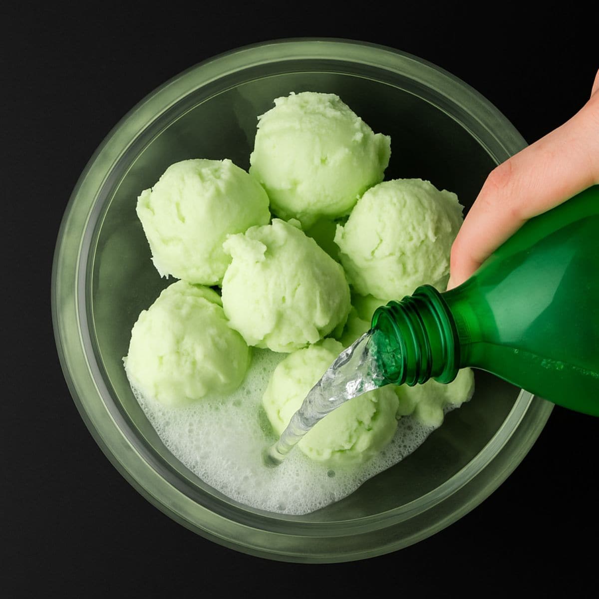Light soda pours over scoops of green sherbet