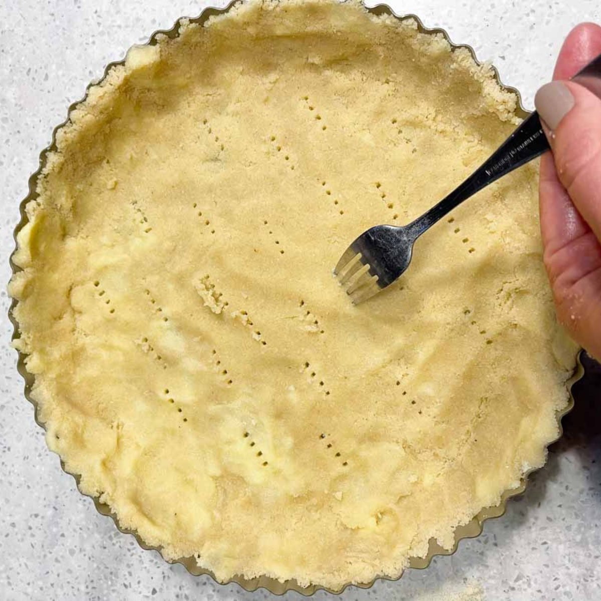 A fork prices an almond tart crust all over.