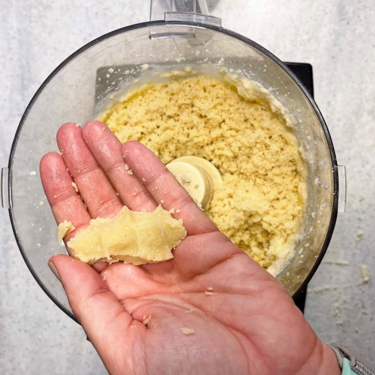 A hand squeezes a handful of almond tart dough.
