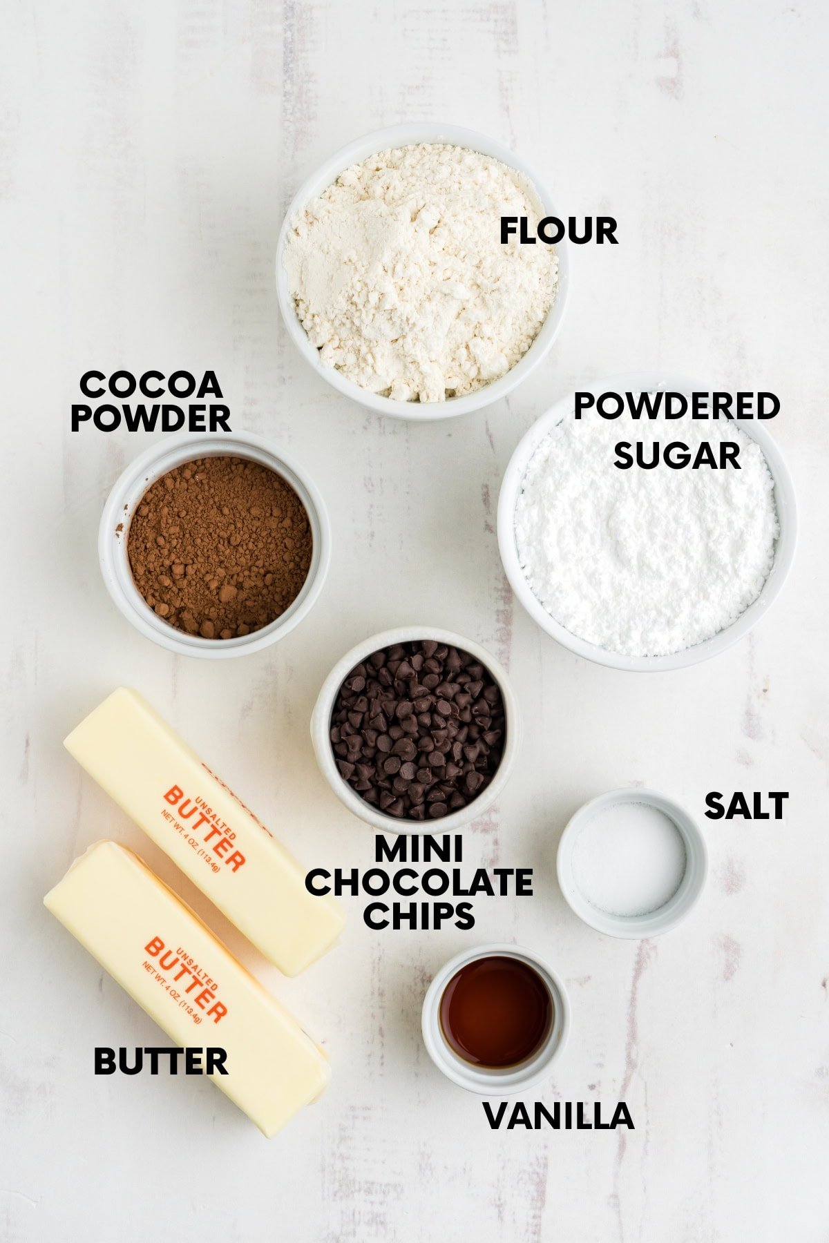 Ingredients for chocolate snowball cookies: flour, cocoa powder, powdered sugar, mini chocolate chips, butter, salt, vanilla.