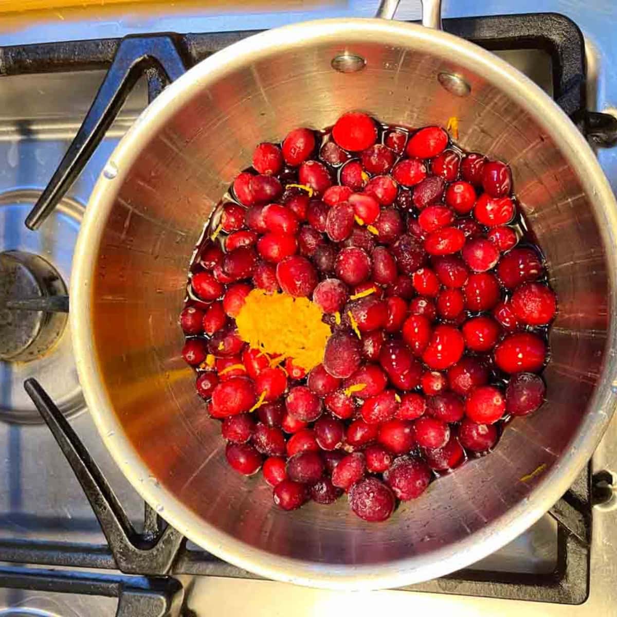 Cranberries in a pot with orange zest.