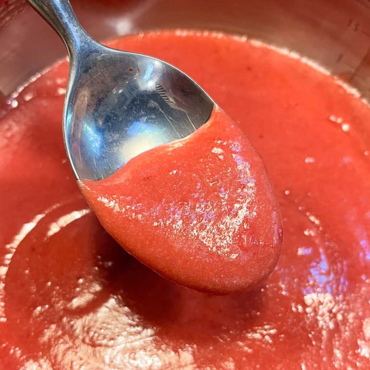 A spoon scoops up a bit of cranberry curd.