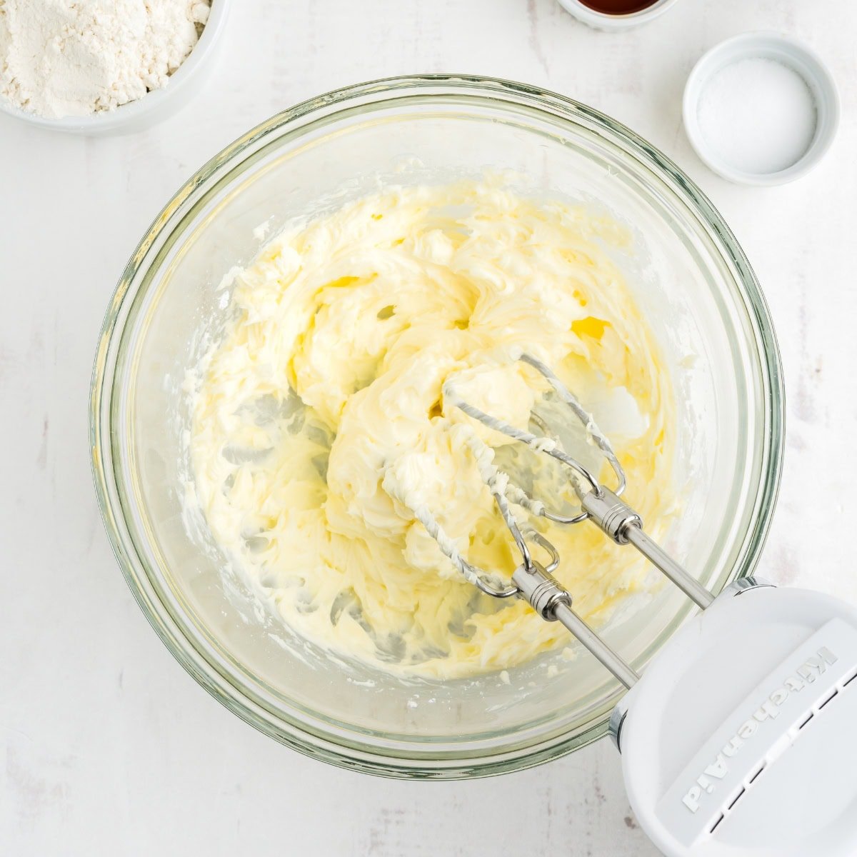 An electric mixer creams butter and powdered sugar.