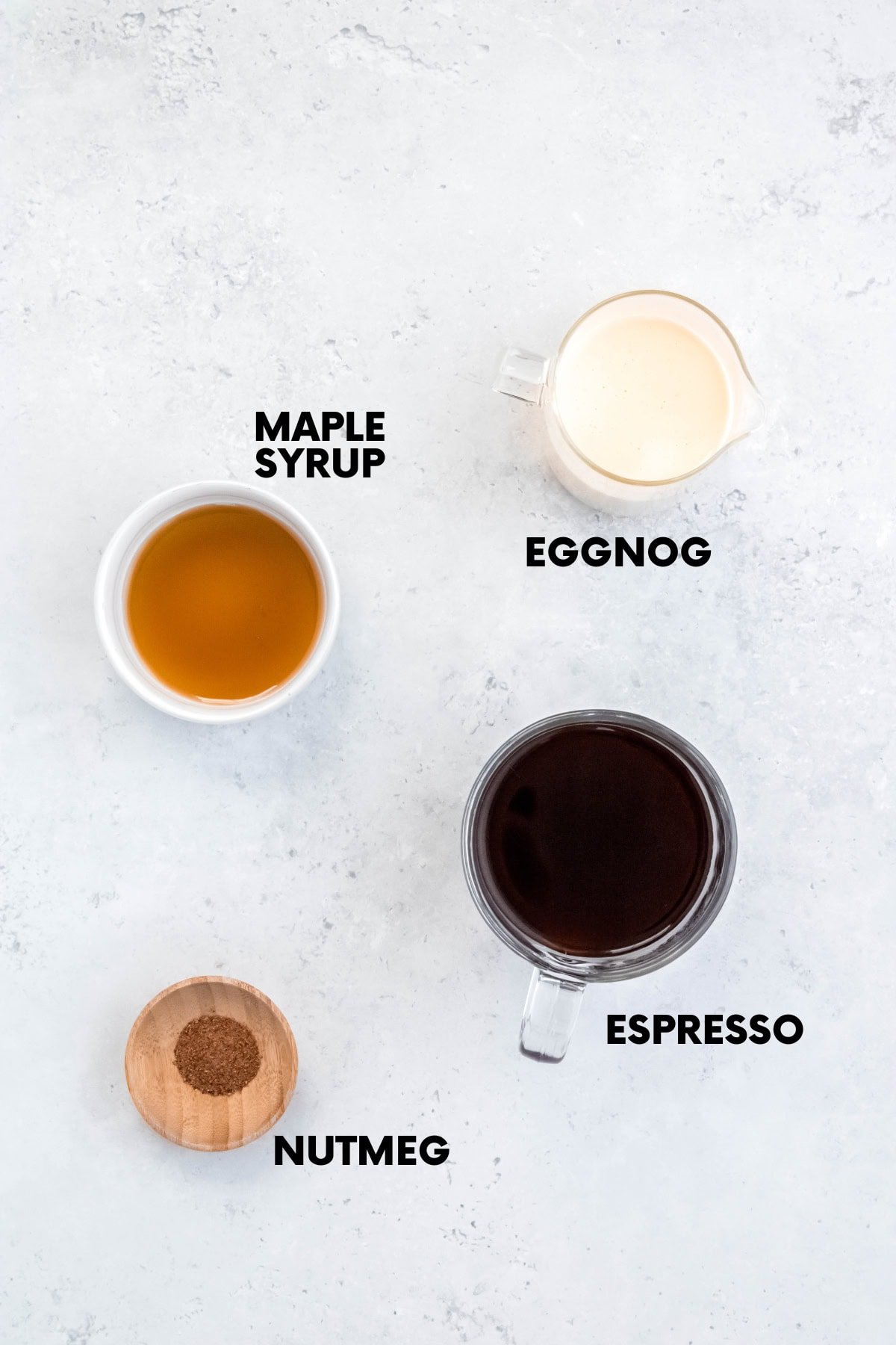 Ingredients for an eggnog latte recipe: eggnog, maple syrup, espresso, nutmeg.
