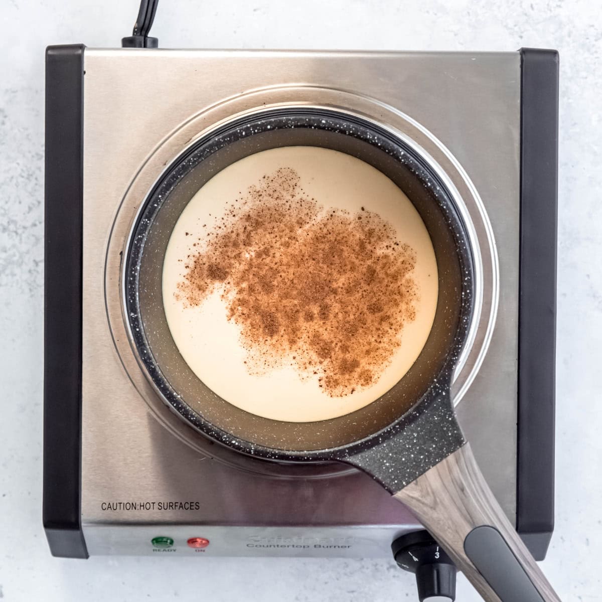 Eggnog, maple syrup, and nutmeg in an enameled saucepan.