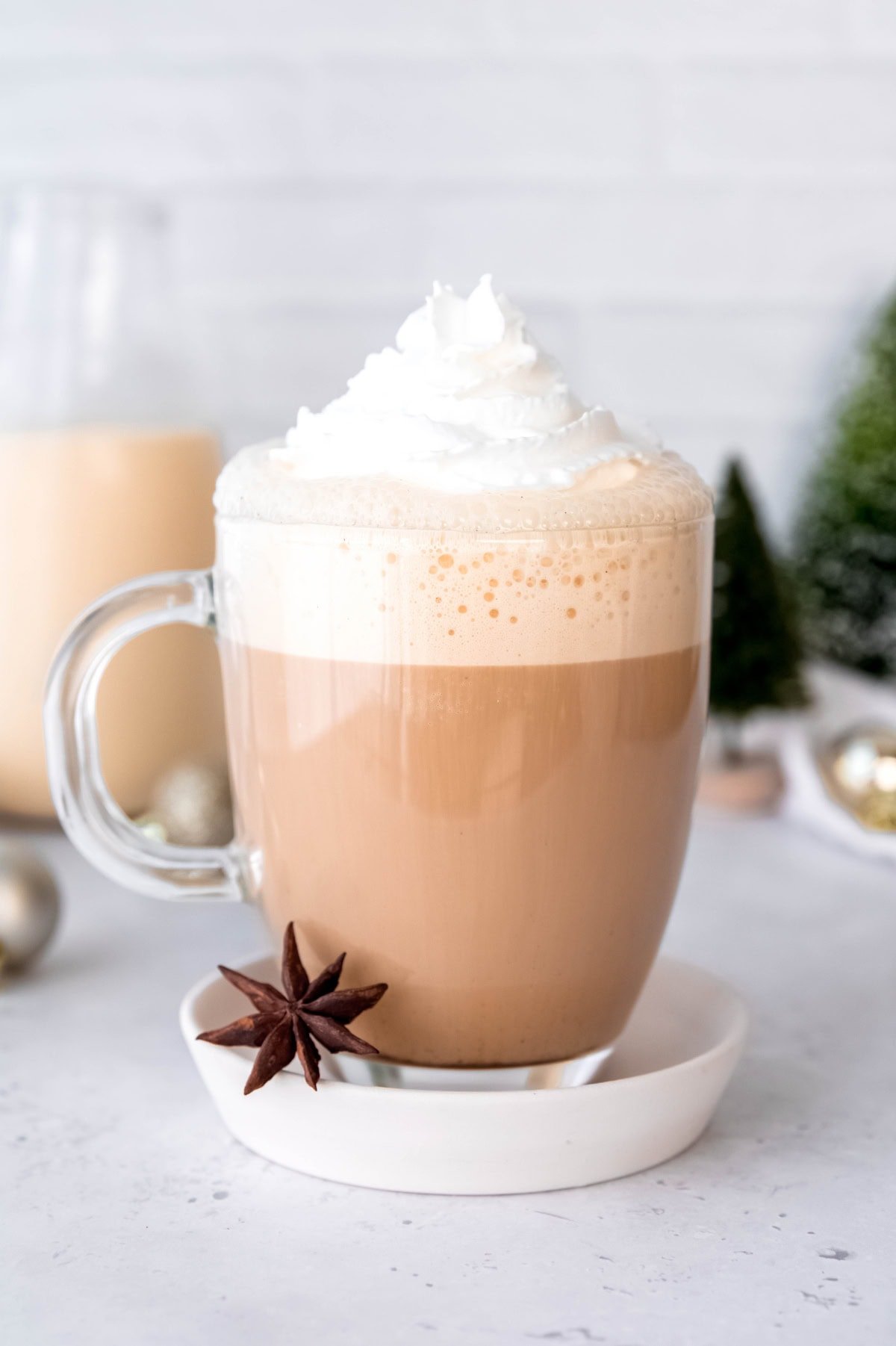 A glass mug of eggnog latte topped with a swirl of whipped cream.