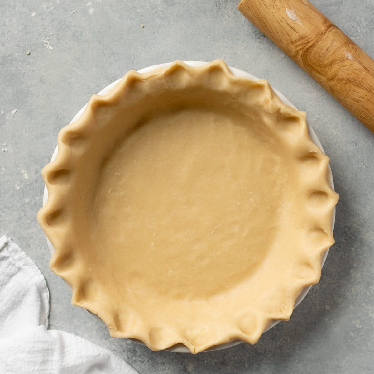 An all-butter pie crust pressed into a pie pan with fluted edges, before baking.