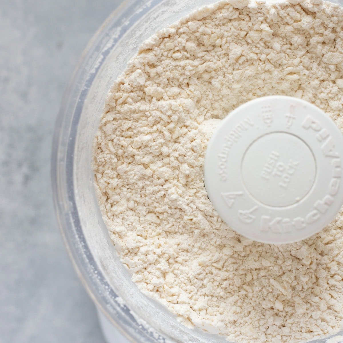 Dry ingredients for gluten-free pie crust recipe in the basin of a food processor.