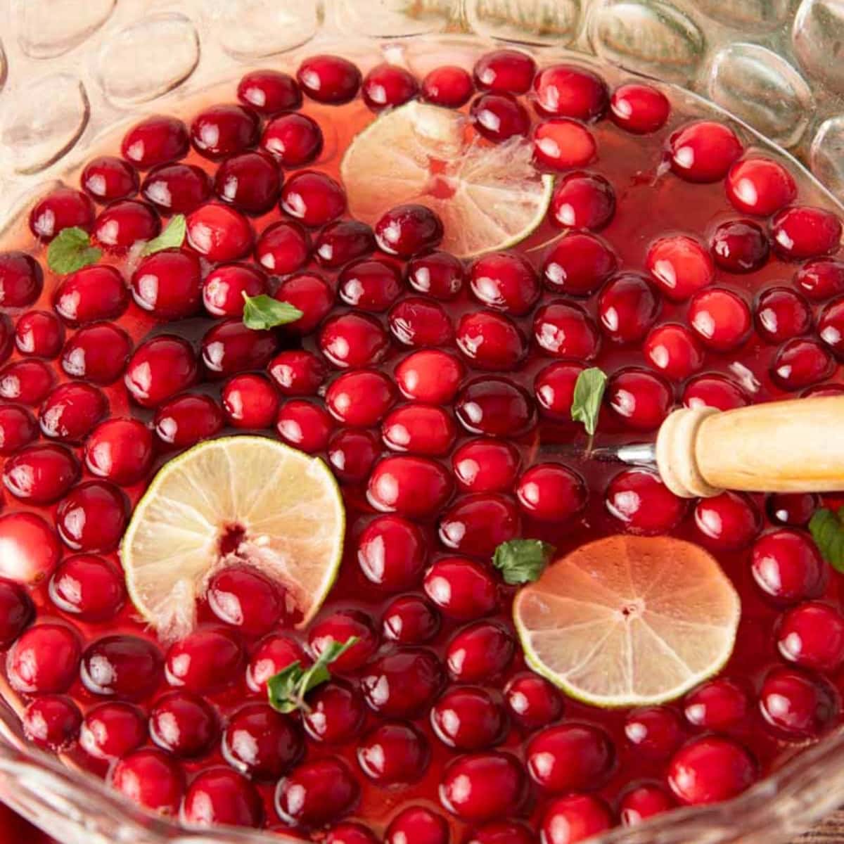 A punch bowl full of jingle juice, garnished with lime slices and fresh mint.