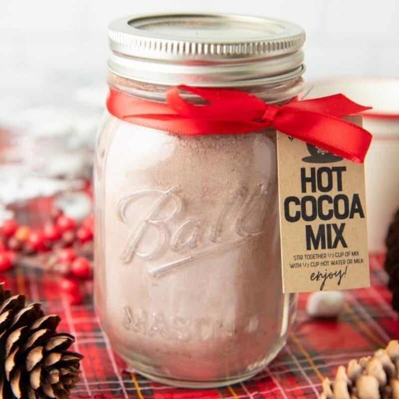 A jar of hot chocolate mix tied with a red ribbon with a kraft paper tag.