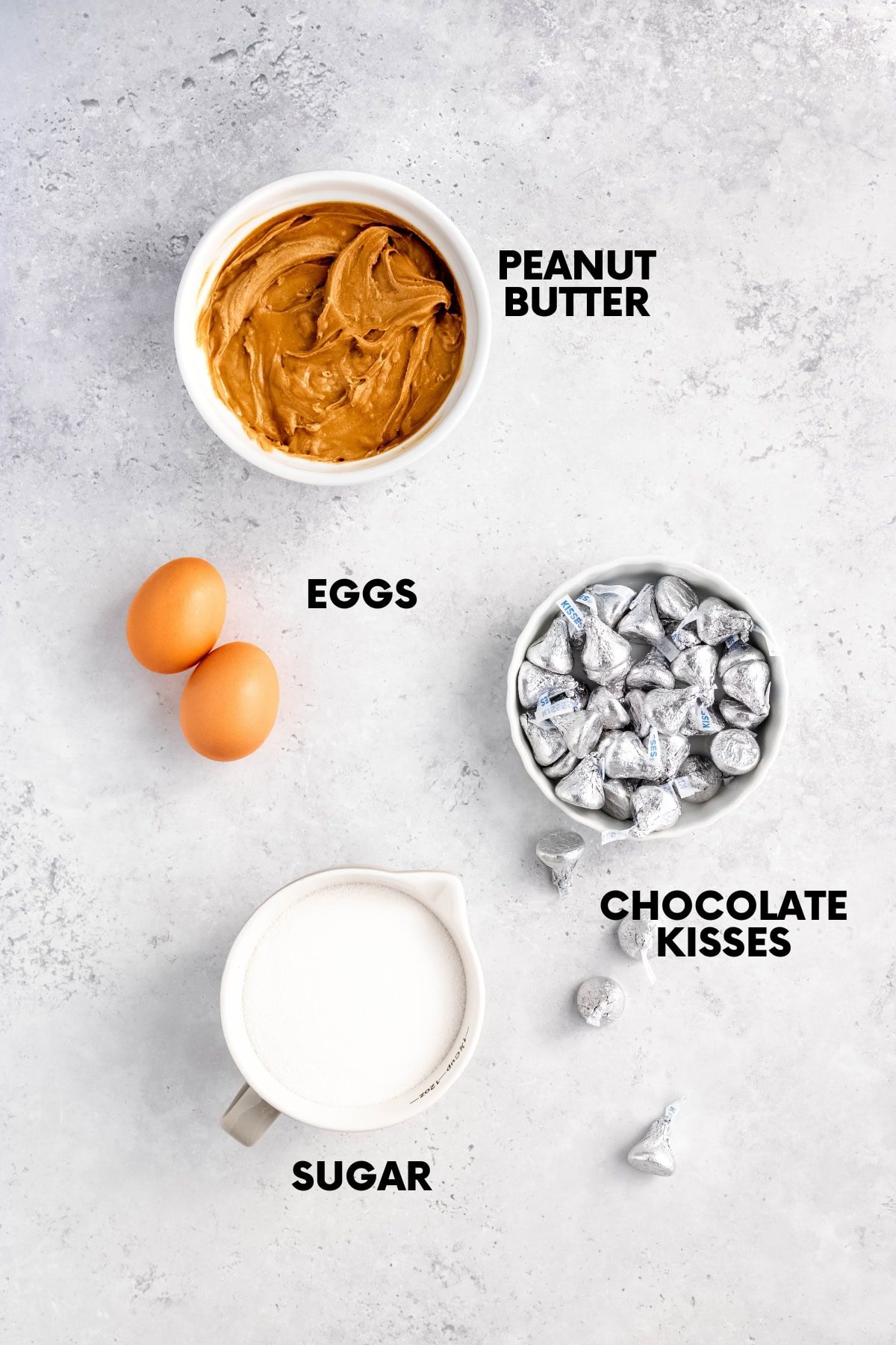 Ingredients for peanut butter kiss cookies: peanut butter, eggs, sugar, and chocolate kisses.