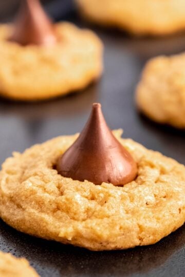 Peanut butter kiss cookies on a dark gray baking sheet.