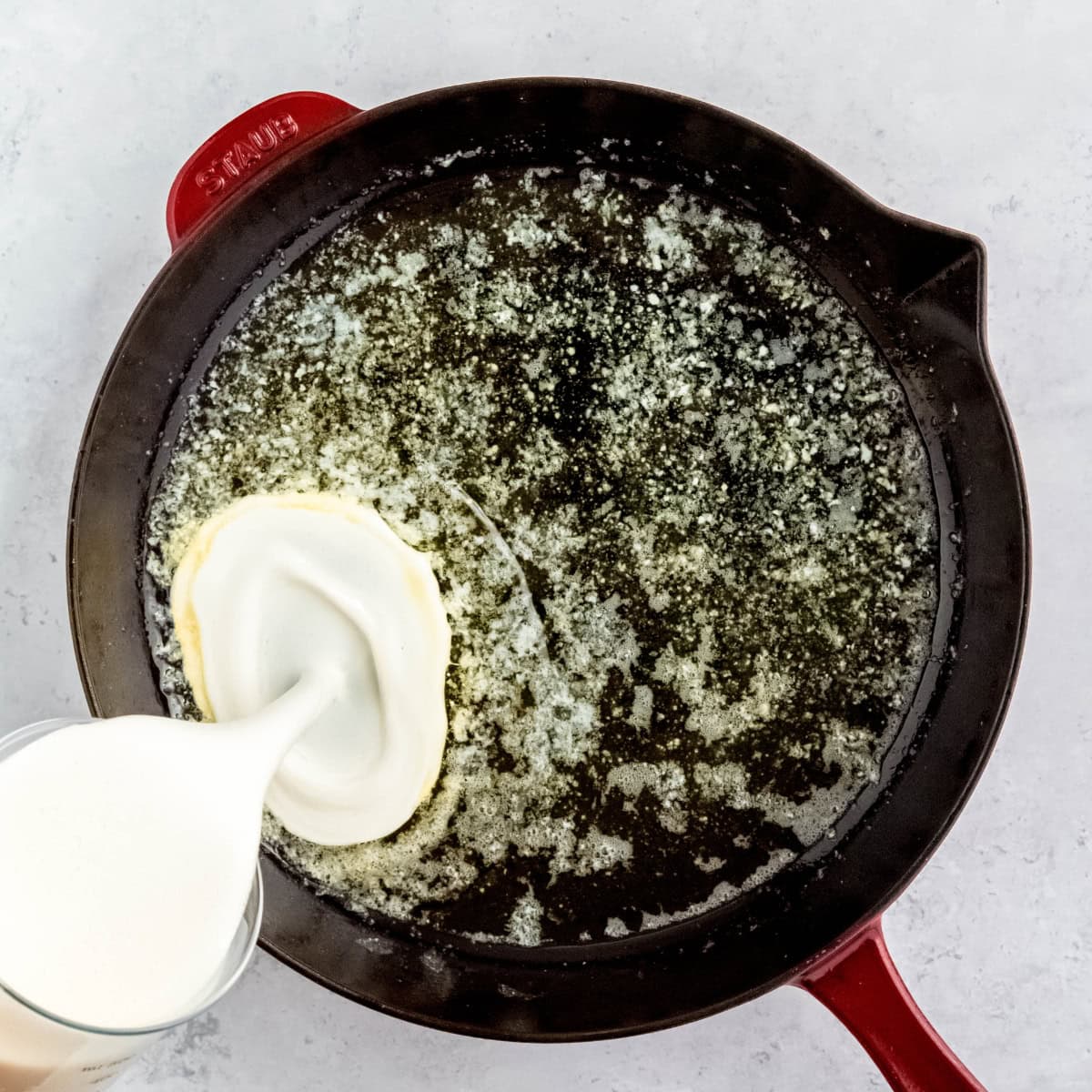 Pannukakku batter pours into a hot buttered skillet.