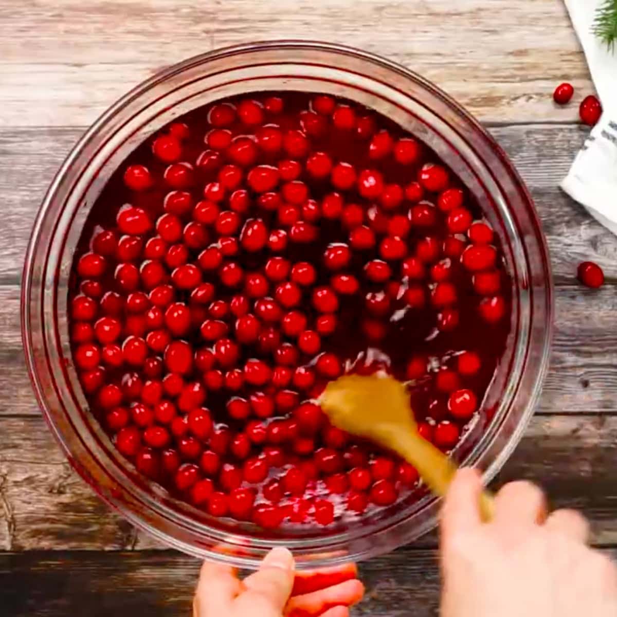 A wooden spoon stirs frozen cranberries into jingle juice.