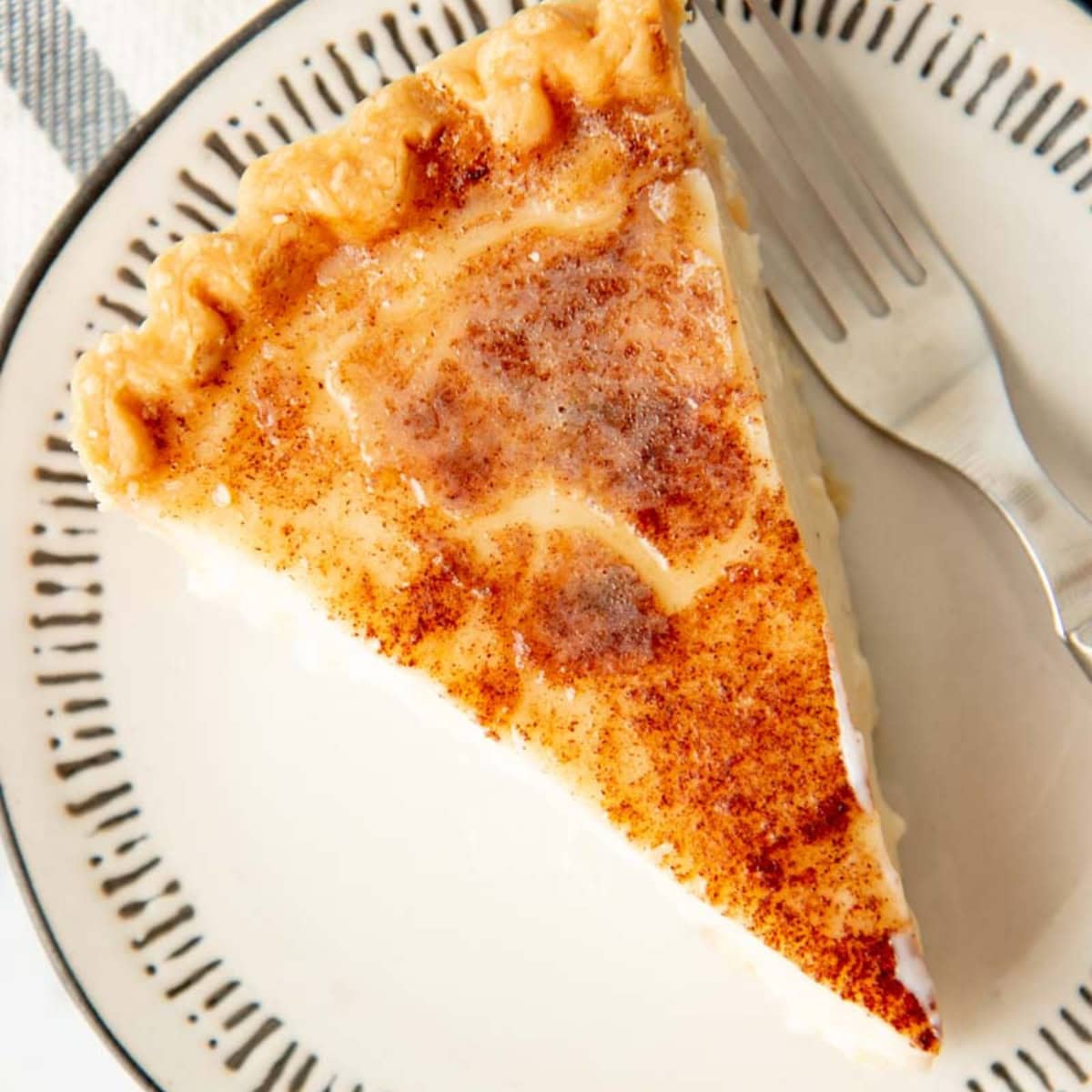 A slice of sugar cream pie with a broiled, browned top.