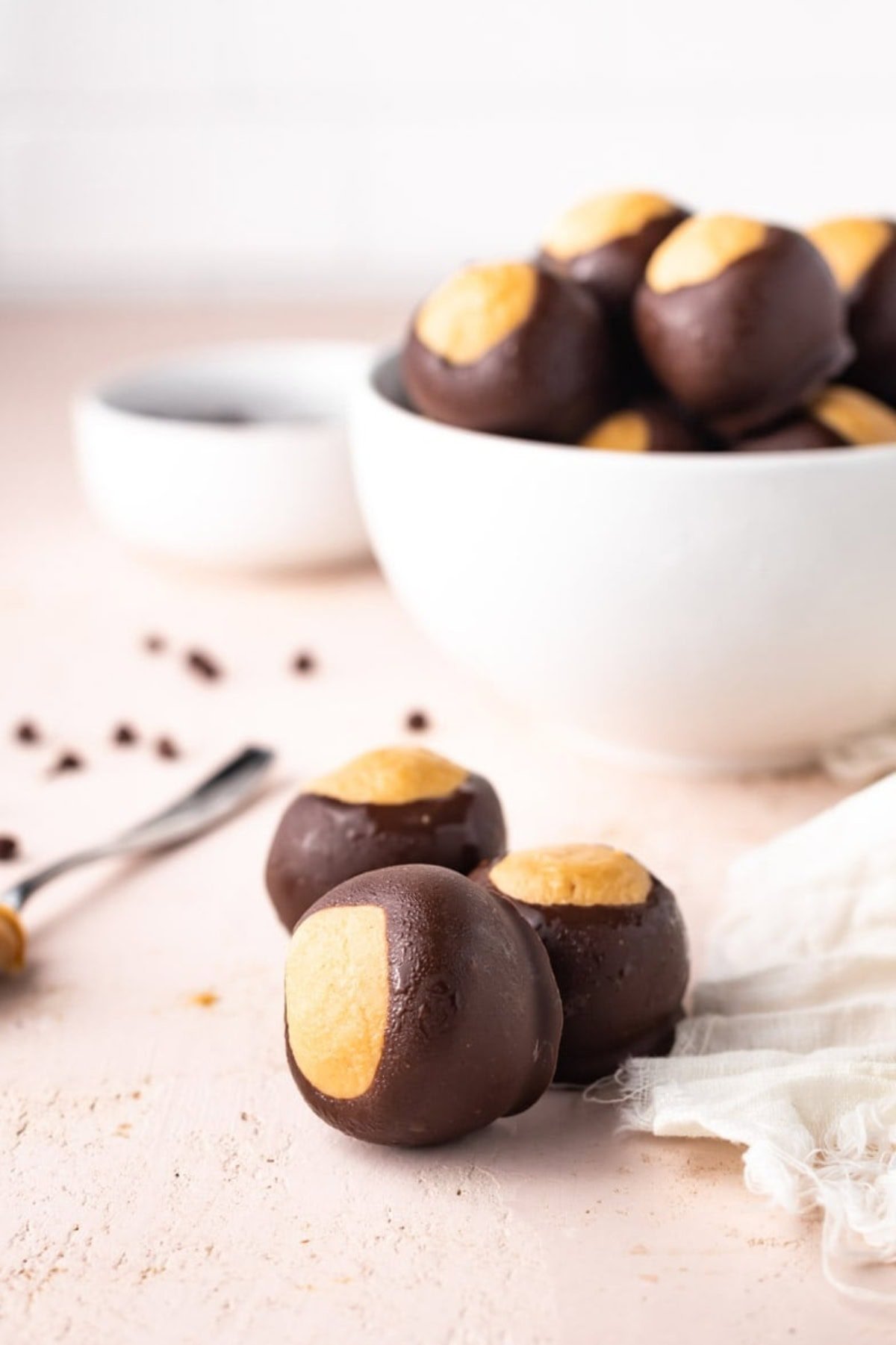 Three buckeye balls in front of a bowl of more candy.
