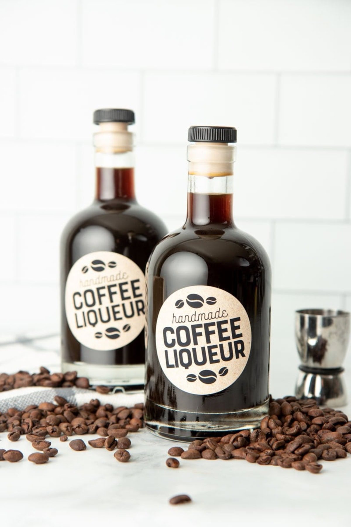 Two bottles of a kahlua recipe, surrounded by coffee beans.
