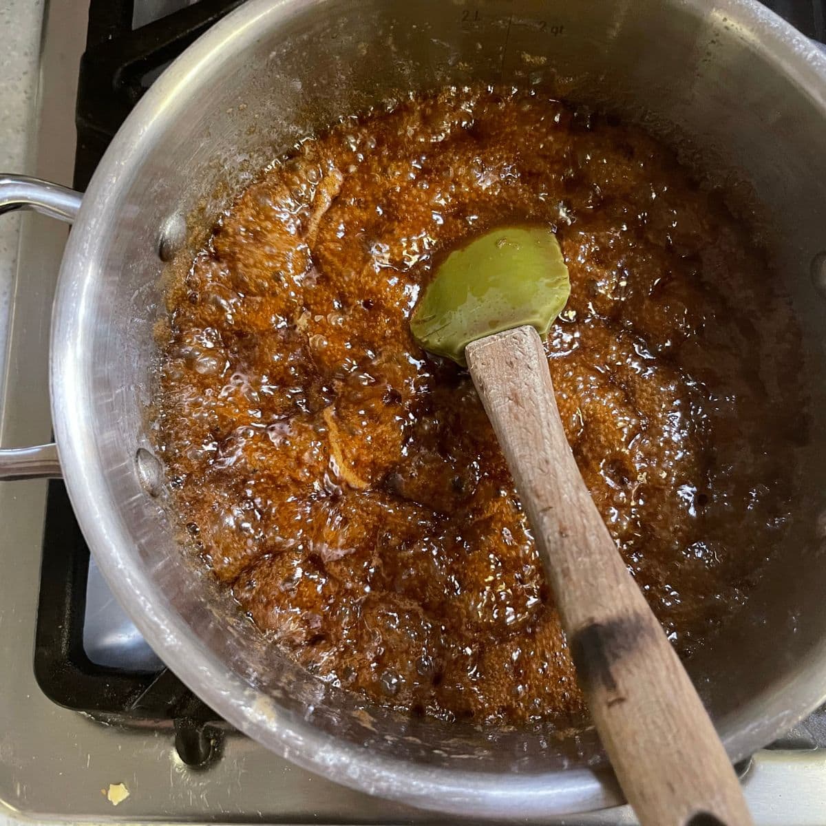 Toffee bubbles away on the stove with a rubber spatula stirring the mixture.