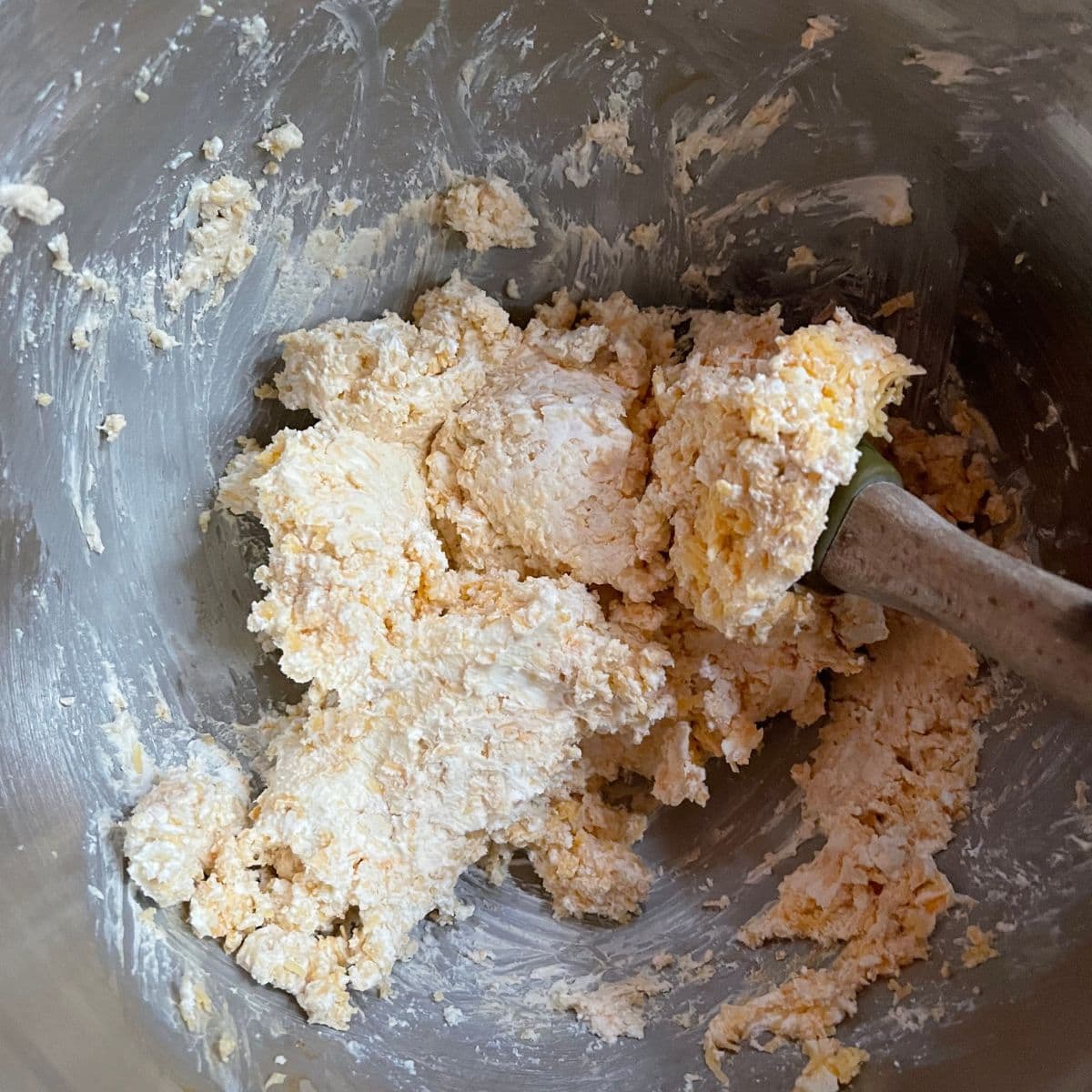 A rubber spatula stirs the ingredients for a simple cheese ball.