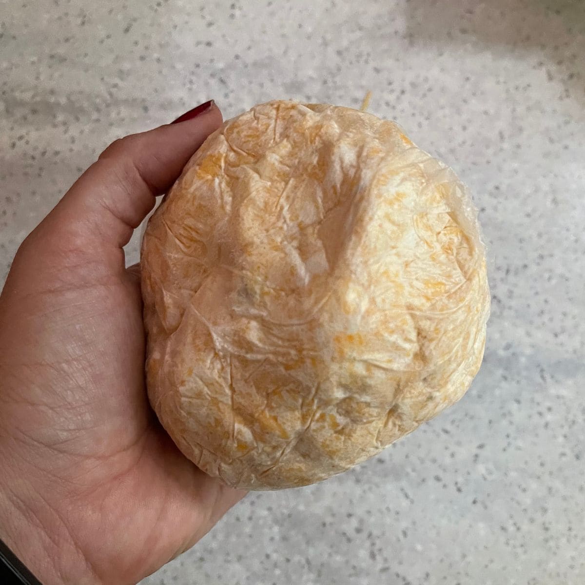 A cheese ball wrapped in plastic wrap.