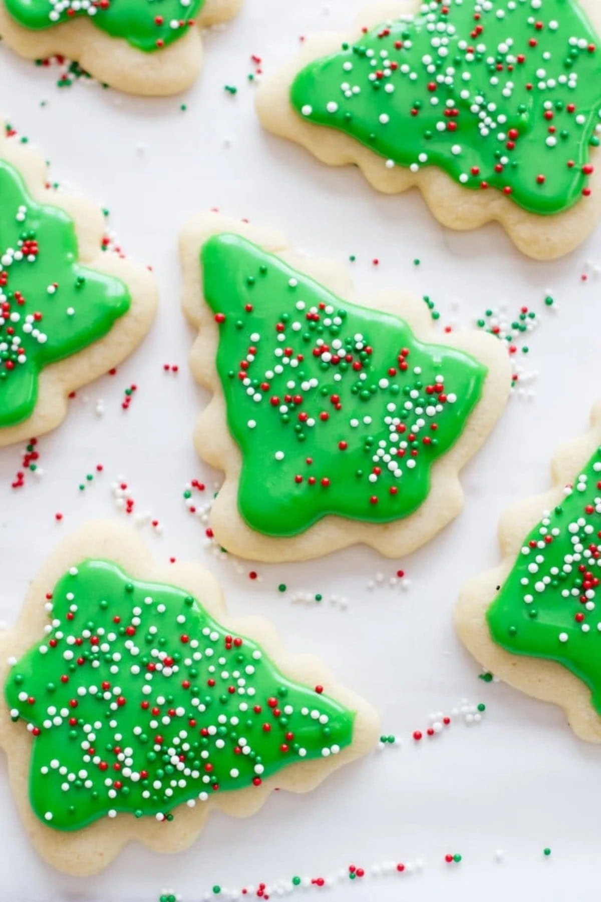 A spread of cut-out cookies, decorated with green frosting and red, white, and green sprinkles.