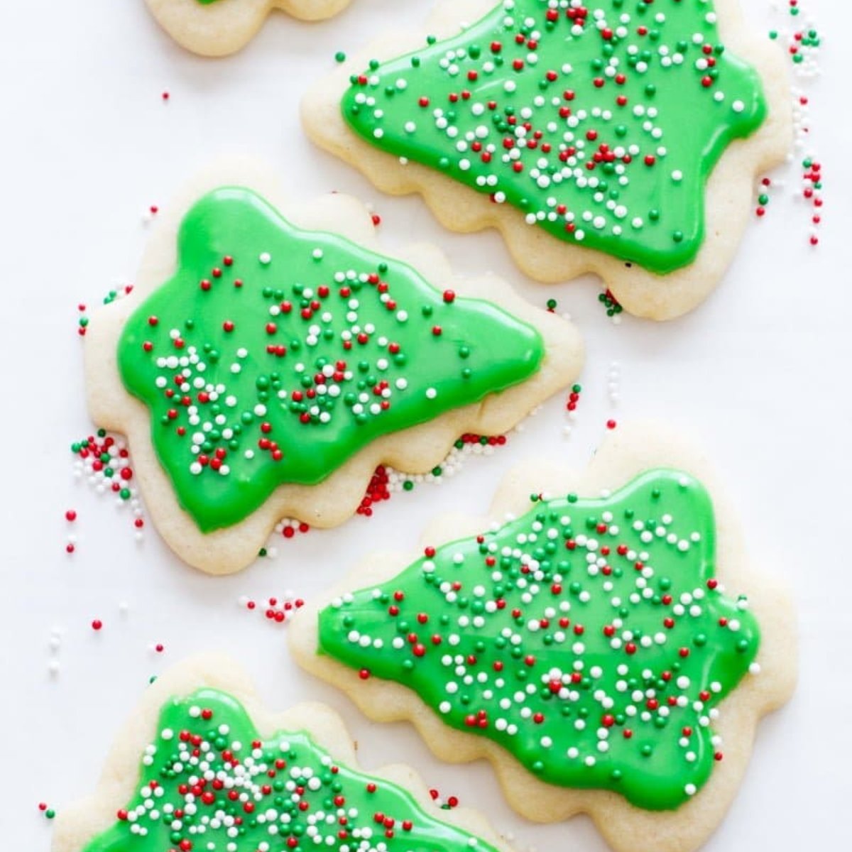 A line of cut-out cookies decorated to look like Christmas trees.