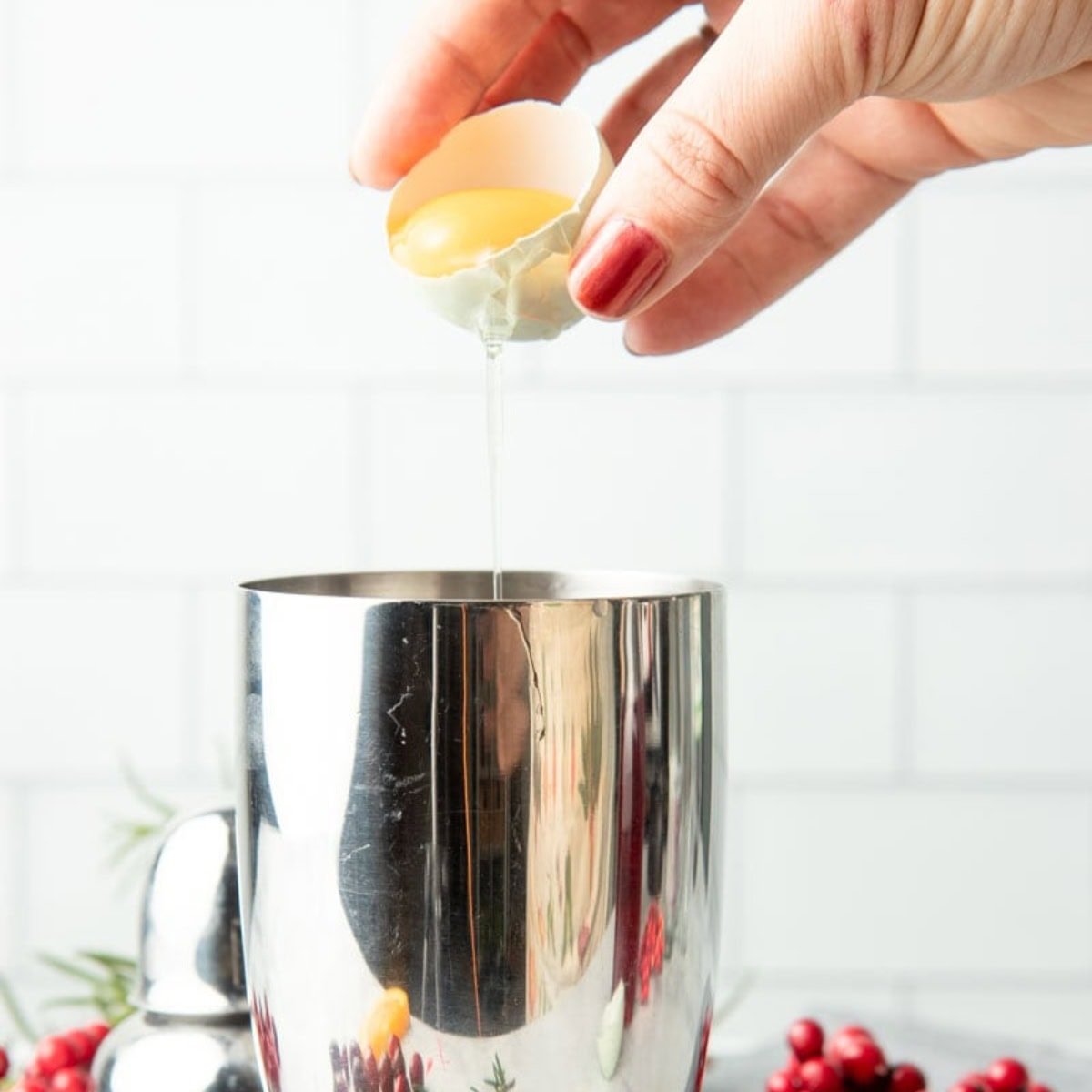 A hand pours an egg white into a cocktail shaker.