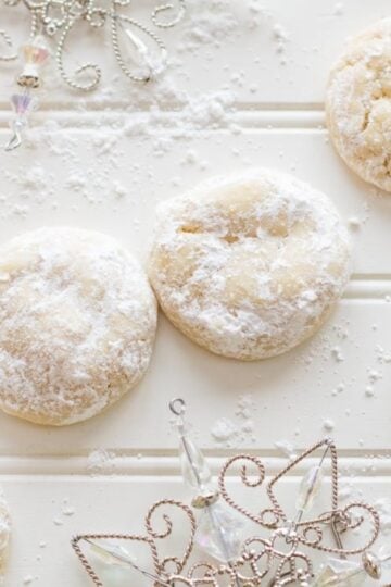 Lemon crinkle cookies on a white background near decorative snowflakes.
