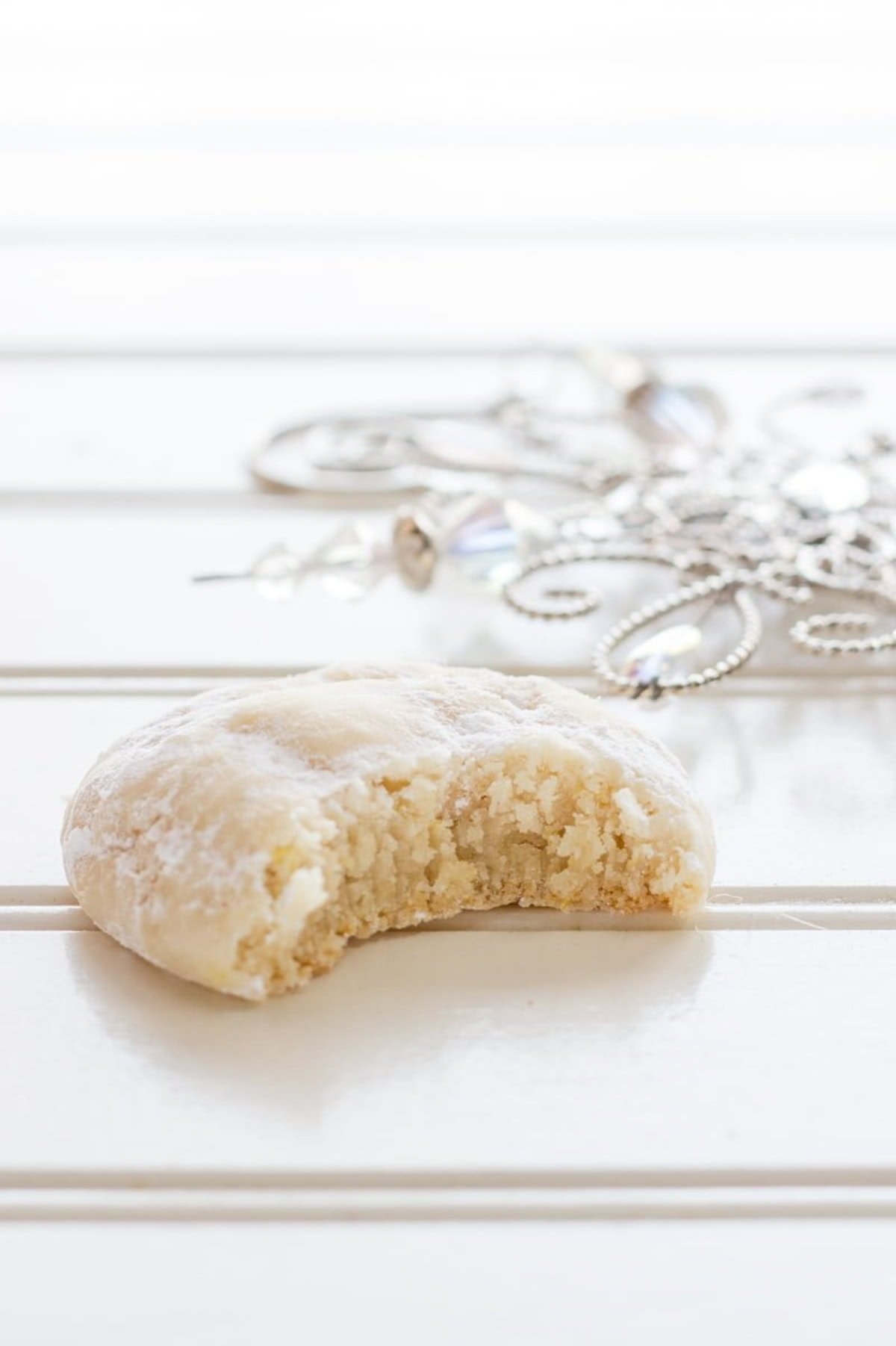 A lemon crinkle cookie with a bite taken out of it.