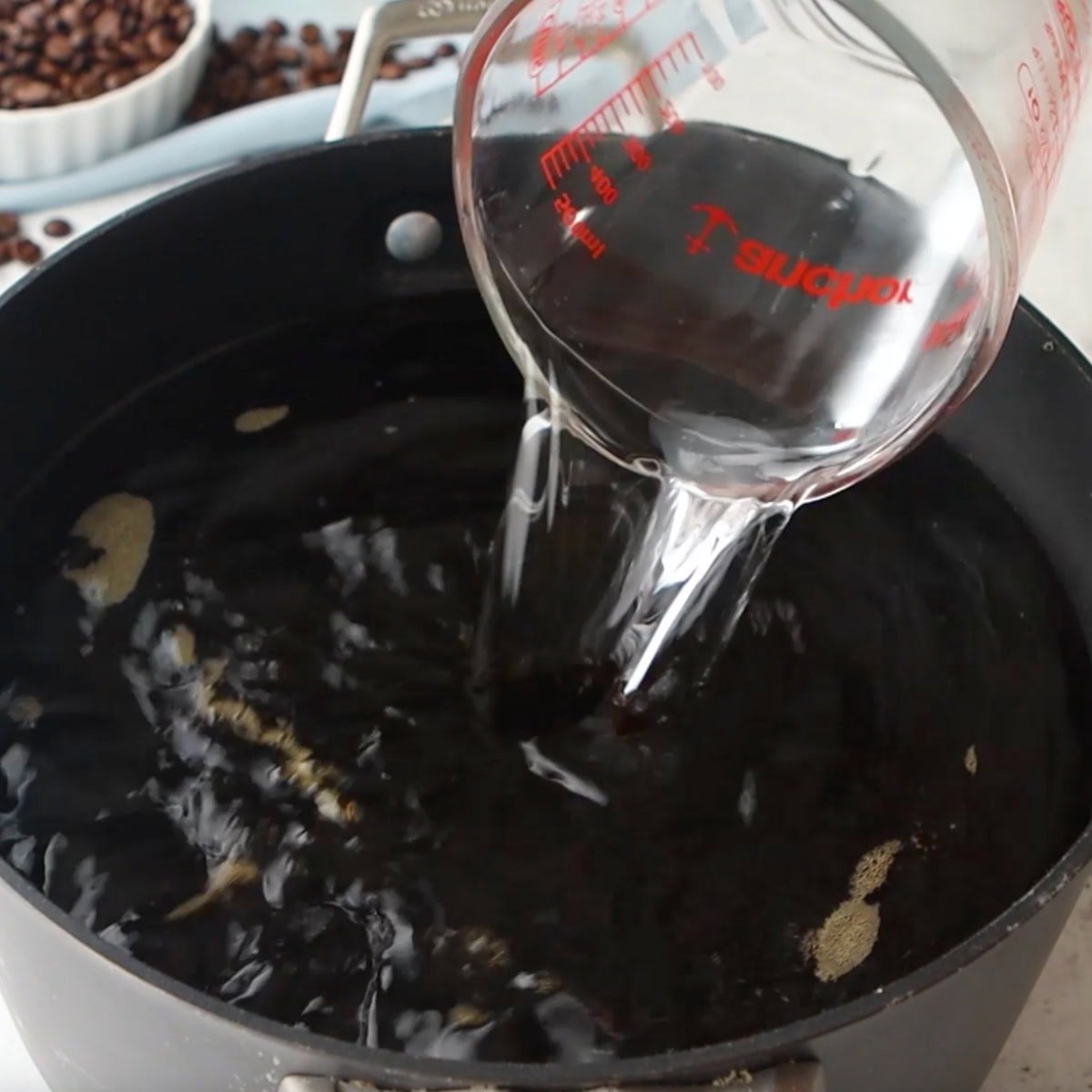 Grain alcohol pours into a coffee syrup for a kahlua recipe.
