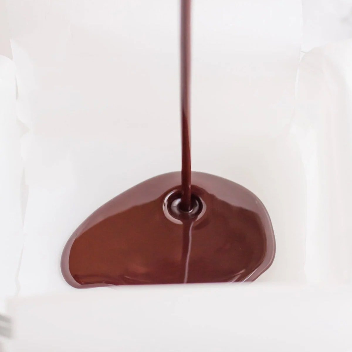 Vegan fudge pours into a parchment-lined pan.