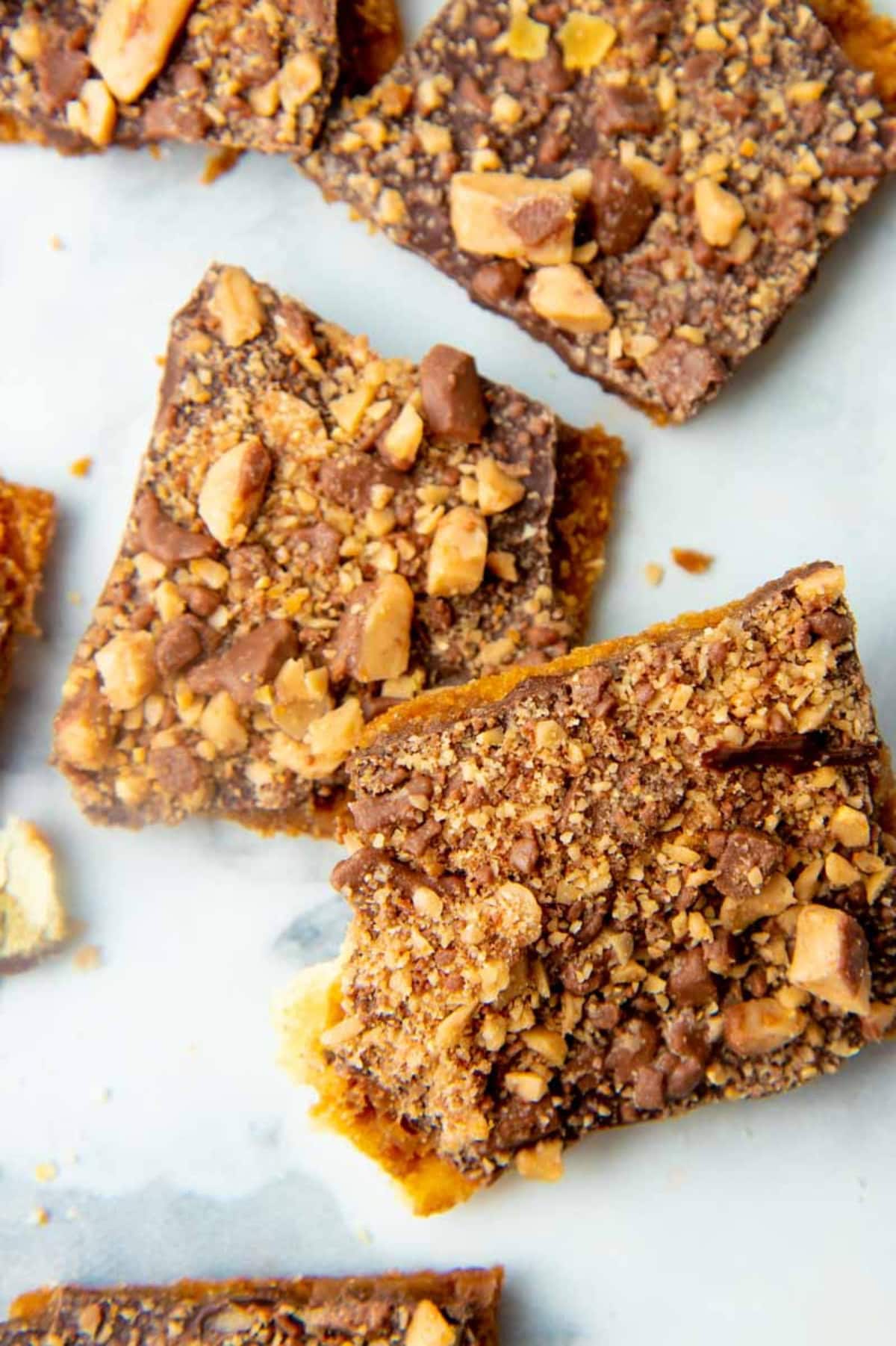 Broken pieces of saltine cracker toffee on a marble countertop.