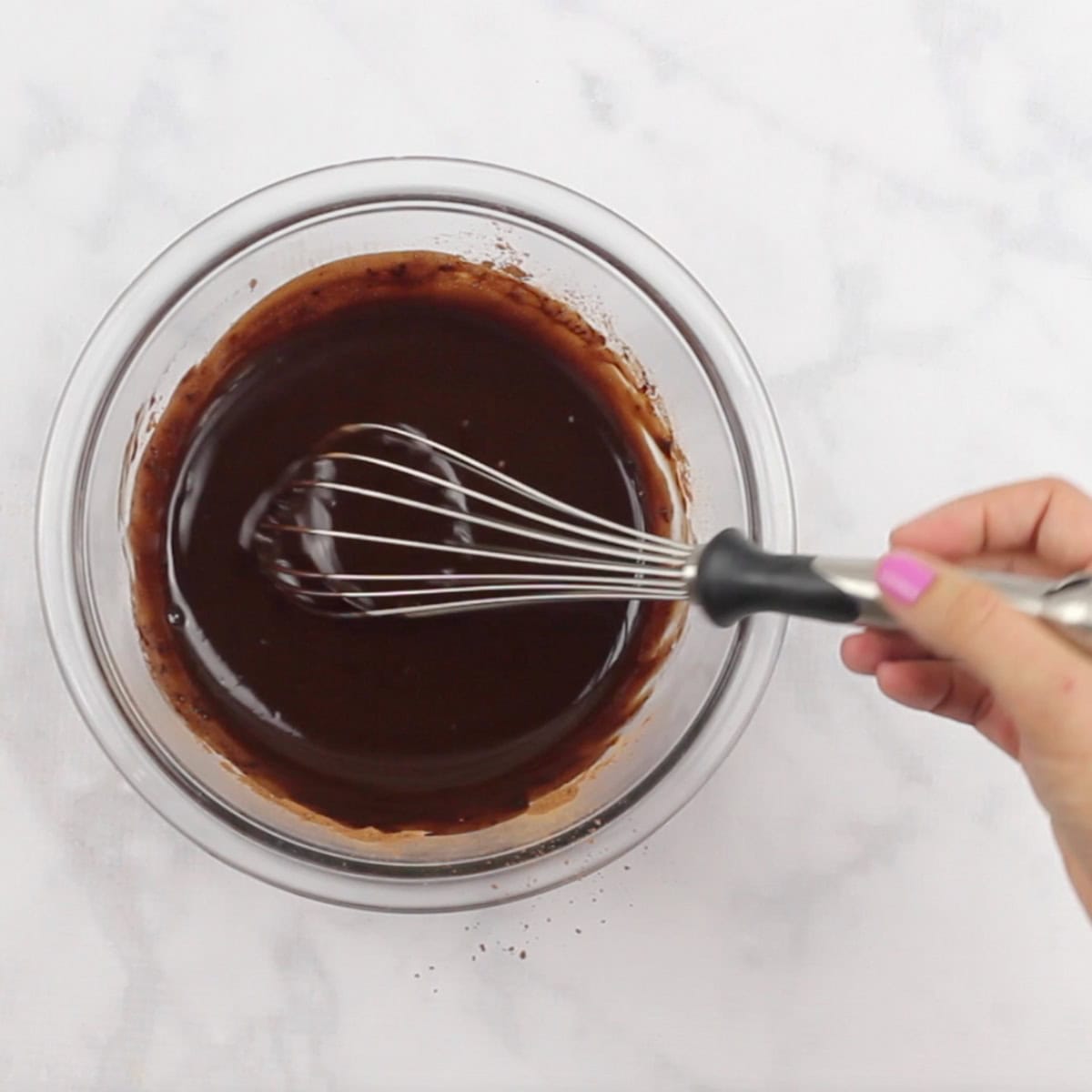 A hand whisks the ingredients for a vegan fudge recipe.